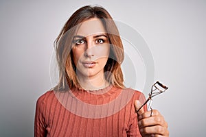 Young beautiful brunette woman using eyelash curler over isolated white background with a confident expression on smart face