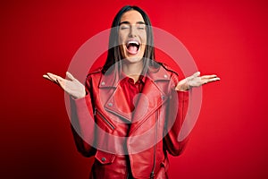 Young beautiful brunette woman wearing casual jacket standing over isolated red background celebrating mad and crazy for success