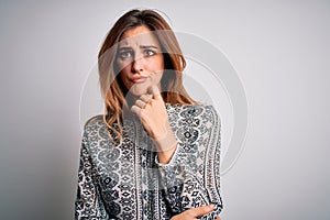 Young beautiful brunette woman wearing casual shirt standing over isolated white background with hand on chin thinking about