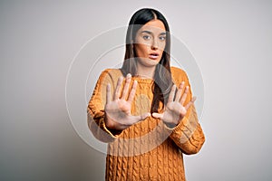 Young beautiful brunette woman wearing casual sweater over isolated white background Moving away hands palms showing refusal and