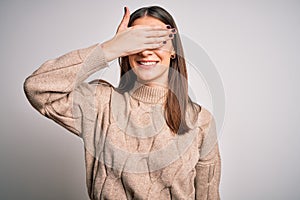 Young beautiful brunette woman wearing casual sweater standing over white background smiling and laughing with hand on face