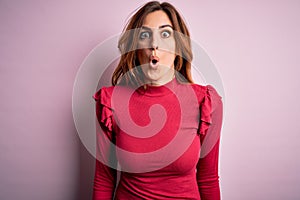 Young beautiful brunette woman wearing casual sweater stnding over pink background afraid and shocked with surprise expression,