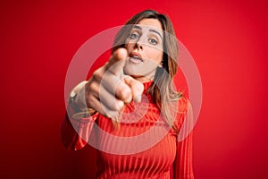 Young beautiful brunette woman wearing casual turtleneck sweater over red background pointing displeased and frustrated to the