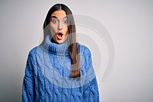 Young beautiful brunette woman wearing casual turtleneck sweater over white background afraid and shocked with surprise