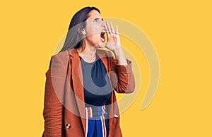 Young beautiful brunette woman wearing elegant clothes shouting and screaming loud to side with hand on mouth