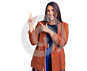 Young beautiful brunette woman wearing elegant clothes smiling and looking at the camera pointing with two hands and fingers to