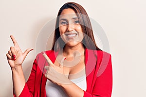 Young beautiful brunette woman wearing elegant jacket smiling and looking at the camera pointing with two hands and fingers to the