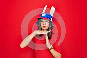 Young beautiful brunette woman wearing united states hat celebrating independence day Doing time out gesture with hands,
