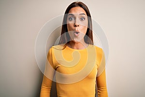 Young beautiful brunette woman wearing yellow casual t-shirt over white background afraid and shocked with surprise expression,