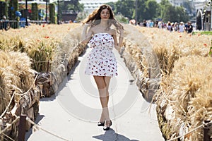 Young beautiful brunette woman in white dress walking on the street