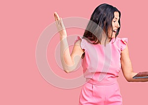 Young beautiful brunette woman working using laptop celebrating victory with happy smile and winner expression with raised hands