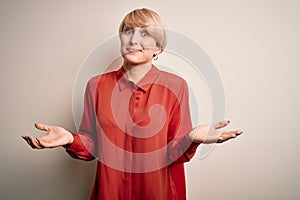 Young beautiful business blonde woman with short hair standing over isolated background clueless and confused expression with arms