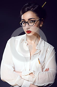 Young beautiful business lady with updo hair wearing white silk blouse and trendy glasses
