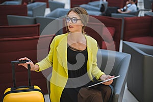 Young beautiful business woman in the airport lounge uses a smartphone and tablet.