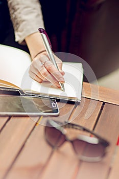 Young beautiful business woman holding pen on a notepad, close up on her hand, working in downtow