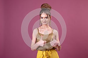 Young beautiful business woman over pink background success sign doing positive gesture with hand, thumbs up smiling and happy.