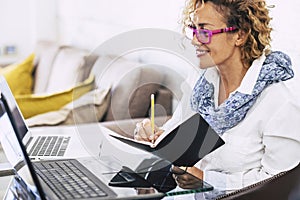 Young beautiful business woman smile and work with two different laptop - modern alternative office at home for independent people photo