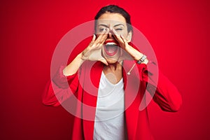 Young beautiful business woman standing over red isolated background Shouting angry out loud with hands over mouth