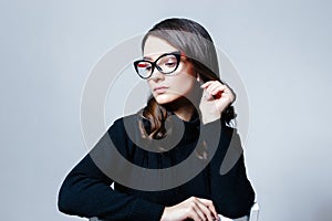 Young beautiful business woman in stylish glasses posing in studio.