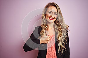 Young beautiful business woman wearing elegant jacket standing over pink isolated background doing happy thumbs up gesture with