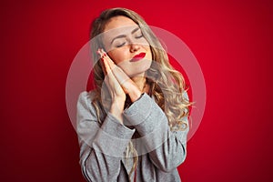 Young beautiful business woman wearing elegant jacket standing over red  background sleeping tired dreaming and posing