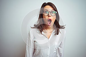 Young beautiful business woman wearing glasses over isolated background afraid and shocked with surprise expression, fear and