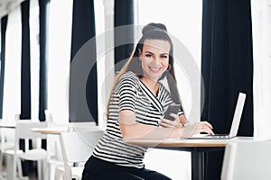 Young beautiful business woman working on her laptop indoors, smiling adult woman is using a laptop in sidewalk cafe