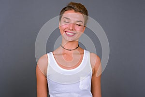 Young beautiful businesswoman with blond hair against gray background