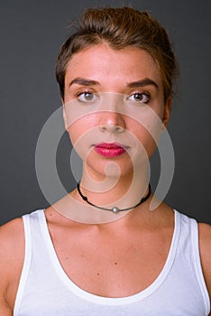 Young beautiful businesswoman with blond hair against gray background