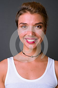 Young beautiful businesswoman with blond hair against gray background