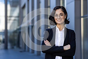 Young beautiful businesswoman in business suit smiling and looking at camera, portrait of successful woman outside