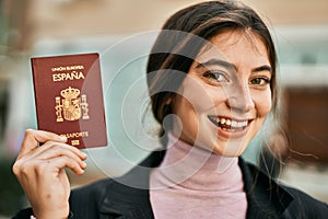 Young beautiful businesswoman smiling happy holding spainish passport at the city