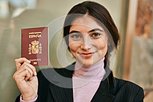 Young beautiful businesswoman smiling happy holding spainish passport at the city