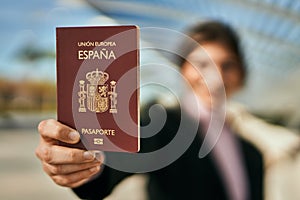 Young beautiful businesswoman smiling happy holding spainish passport at the city