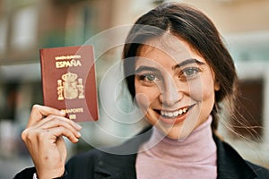 Young beautiful businesswoman smiling happy holding spainish passport at the city