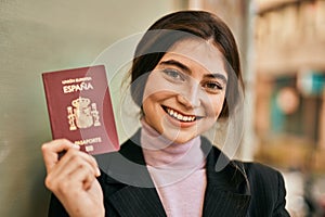 Young beautiful businesswoman smiling happy holding spainish passport at the city