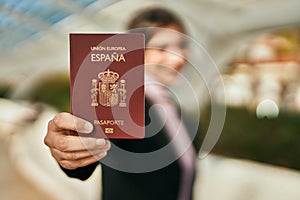 Young beautiful businesswoman smiling happy holding spainish passport at the city