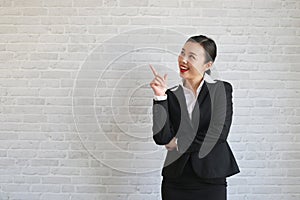 Young beautiful businesswoman smiling looking at camera pointing finger in side over white background