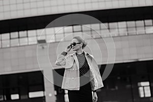 Young beautiful businesswoman with sunglasses, phone, laptop, cup of coffee in the city streets