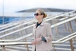 Young beautiful businesswoman with sunglasses, phone, laptop, cup of coffee in the city streets