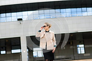 Young beautiful businesswoman with sunglasses, phone, laptop, cup of coffee in the city streets