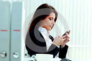 Young beautiful businesswoman typing on her smartphone