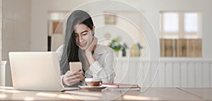 Young beautiful businesswoman using her smartphone while working on her project