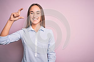 Young beautiful businesswoman wearing elegant shirt standing over isolated pink background smiling and confident gesturing with