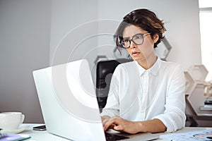 Young beautiful businesswoman working with laptop at workplace in office.