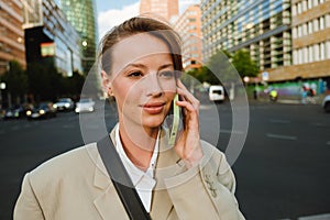 Young beautiful calm business woman talking phone and looking aside