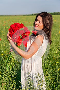 Young beautiful calm girl dreaming on a poppy field, summer outdoor