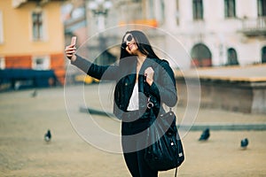 Young beautiful casual girl takes a selfie on her cell phone