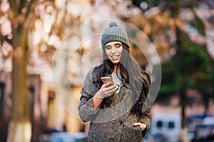 Young beautiful casual girl texting on her cell phone on spring city street