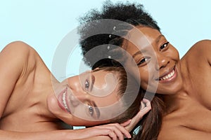Young beautiful caucasian and african women posing lying on top of each other, face to face. Lifestyle of different